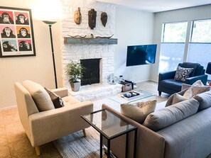 A living room with a fireplace, a sofa, a coffee table, and a television. - 5 bed/5 bath Hiking on Greenbelt Close to Zilker! (Austin)