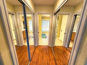A hallway with wooden flooring and white walls, leading to a door with a window. - Serenity Sound House Sandbridge Oasis With Pool (Virginia Beach)