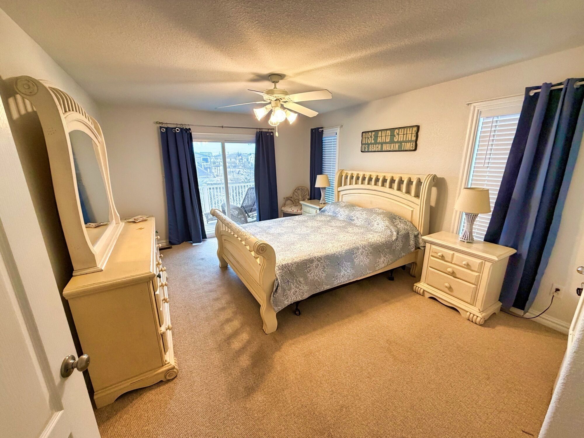 A bedroom with a bed, dresser, mirror, and a ceiling fan.