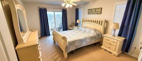 A bedroom with a bed, dresser, mirror, and a ceiling fan.