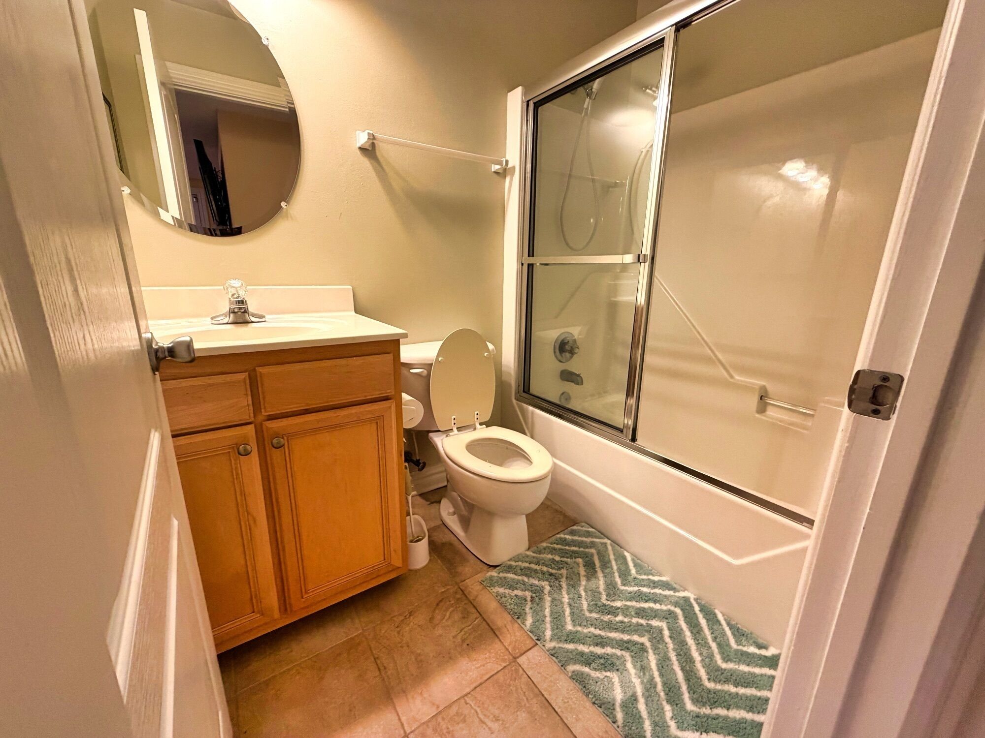A bathroom with a toilet, sink, mirror, and shower area.