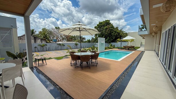 Eine moderne Außenpatio mit Pool, Sitzgelegenheit und überdachtem Bereich.