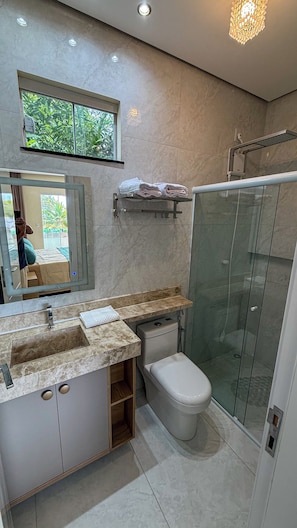 Een moderne badkamer met een douchecabine van glas, een toilet en een wastafel met spiegel erboven.