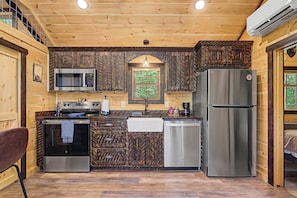 A compact kitchen with a microwave, oven, refrigerator, and dishwasher. - Brand New!  2-bedroom cabin with AC in scenic Sevierville. (Sevierville)