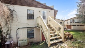 A two-story house with a wooden staircase leading to the front door.