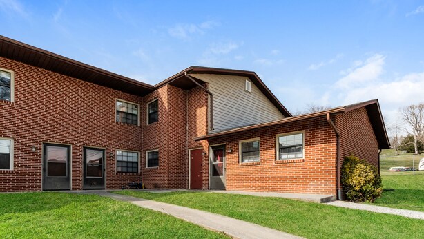 A two-story brick building with a flat roof and a small front yard.