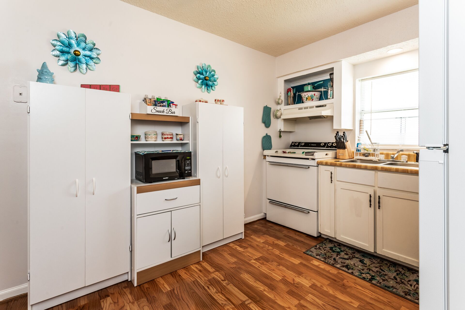 A compact kitchen with white cabinets, a microwave, an oven, and a sink.