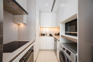 Eine moderne Küche mit weißen Schränken, einem Backofen, einer Mikrowelle und einer Waschmaschine.