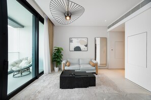 Ein modernes Wohnzimmer mit Glaswand, einem schwarzen Couchtisch, einem hellen Sofa und einer Topfpflanze.