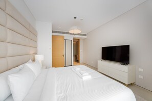 Ein modernes Hotelzimmer mit einem großen Bett, einem Fernseher und einem Kleiderschrank.