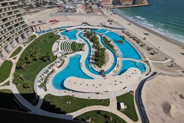 Un complexe hôtelier doté d’une grande piscine centrale, de plusieurs petites piscines et d’une zone de plage.