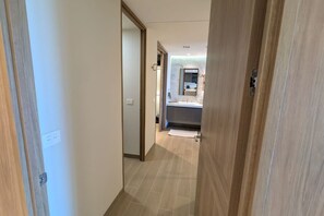 Ein Flur, der zu einem Badezimmer mit Waschbecken und Spiegel führt.
