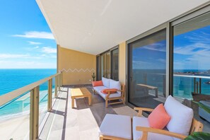 Un balcon avec vue sur la mer, aménagé avec deux chaises et une table.