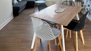 A dining area with a wooden table, white and black chairs, a small round table, and a sofa.