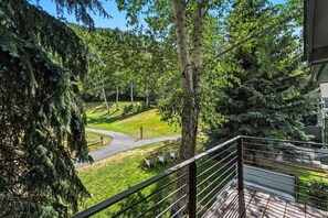 A balcony with a view of a landscaped area with trees and a winding path. - Fairway Escape | Private Hot Tub & Views (Avon)