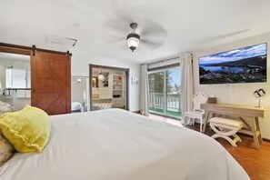 Une chambre à coucher avec un lit, un bureau, une chaise et une vue sur l’extérieur.