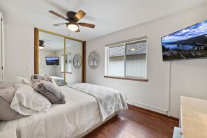 A bedroom with a bed, a ceiling fan, a large mirror, a window with a view, and a television mounted on the wall. - Incredible Water Front Tahoe Keys Home 3BD/2BA (South Lake Tahoe)