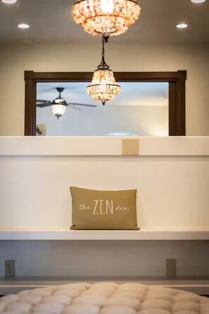 Ein Zimmer mit einer Chandelüster, einem Deckenventilator und einem Kissen mit dem Aufdruck 'the ZEN den'.
