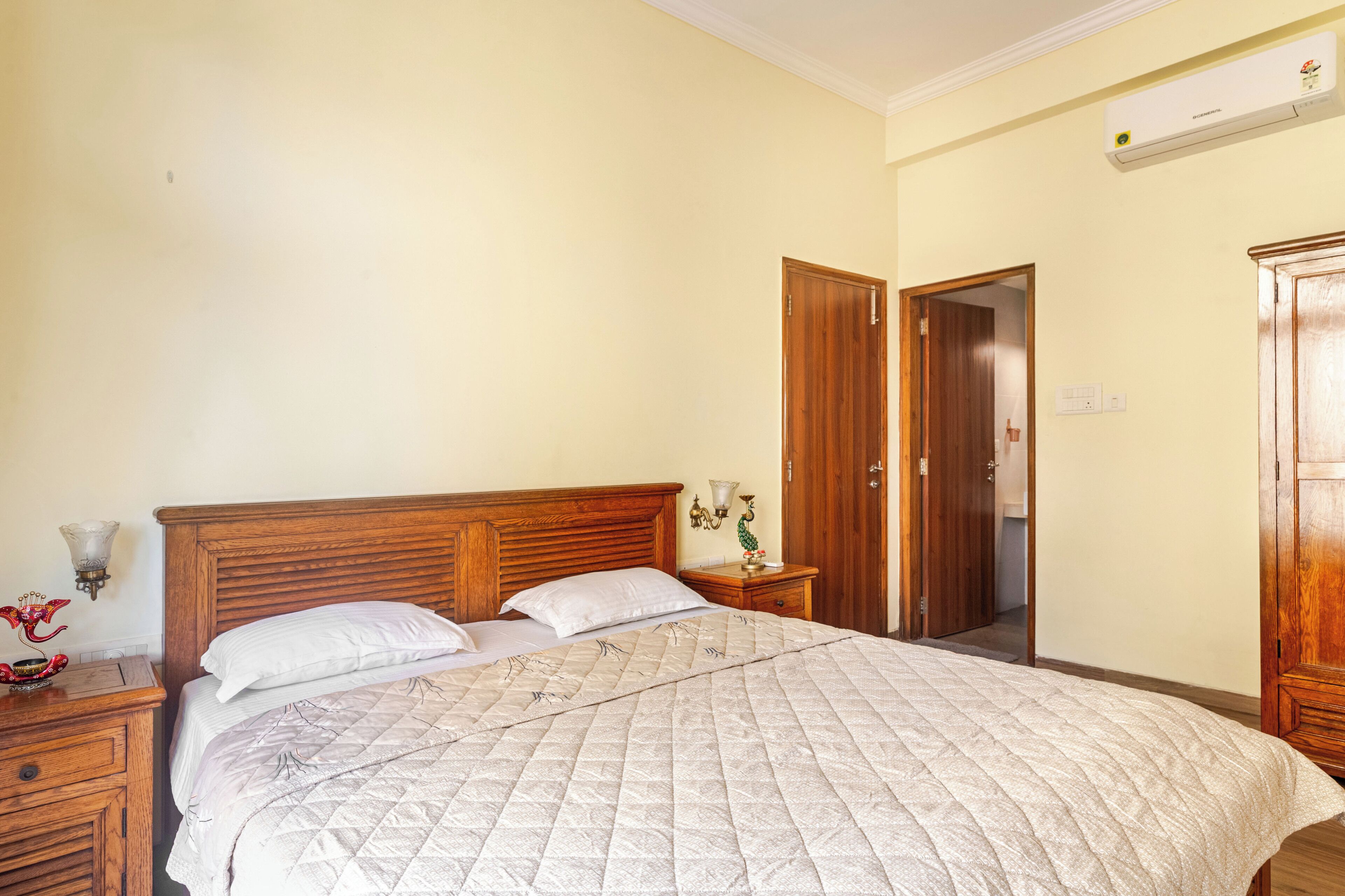 A bedroom with a wooden bed, a nightstand, a wall-mounted lamp, and a wardrobe.