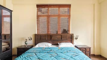 Un dormitorio con cama, dos mesitas de noche, un cabecero de madera y una ventana con persianas.