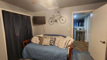 A bedroom with a bed, a ceiling fan, a mounted television, and a bicycle decoration on the wall.