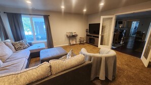 A living room with a sofa, ottoman, and a television. - Spacious 6-bedroom house located on Richmond Lake. (Aberdeen)