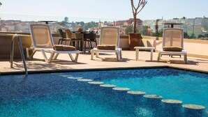 Area piscina sul tetto con poltrone relax e tavolo da pranzo.