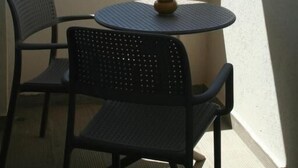 Un balcone con un tavolo rotondo e due sedie, affacciato su una vista cittadina.