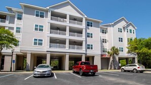 A multi-story hotel with a parking lot, a red pickup truck, and a white sedan. - Furnished Monthly Rental near Folly (Charleston)