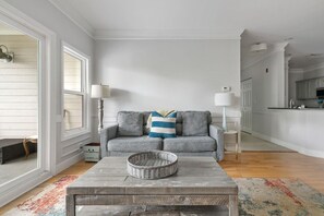 A living room with a grey sofa, two floor lamps, a wooden coffee table, and a colorful rug. - Furnished Monthly Rental near Folly (Charleston)