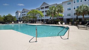 A swimming pool with lounge chairs and a multi-story building in the background. - Furnished Monthly Rental near Folly (Charleston)