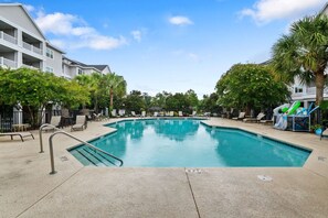 A swimming pool with lounge chairs and palm trees, surrounded by buildings. - Furnished Monthly Rental near Folly (Charleston)