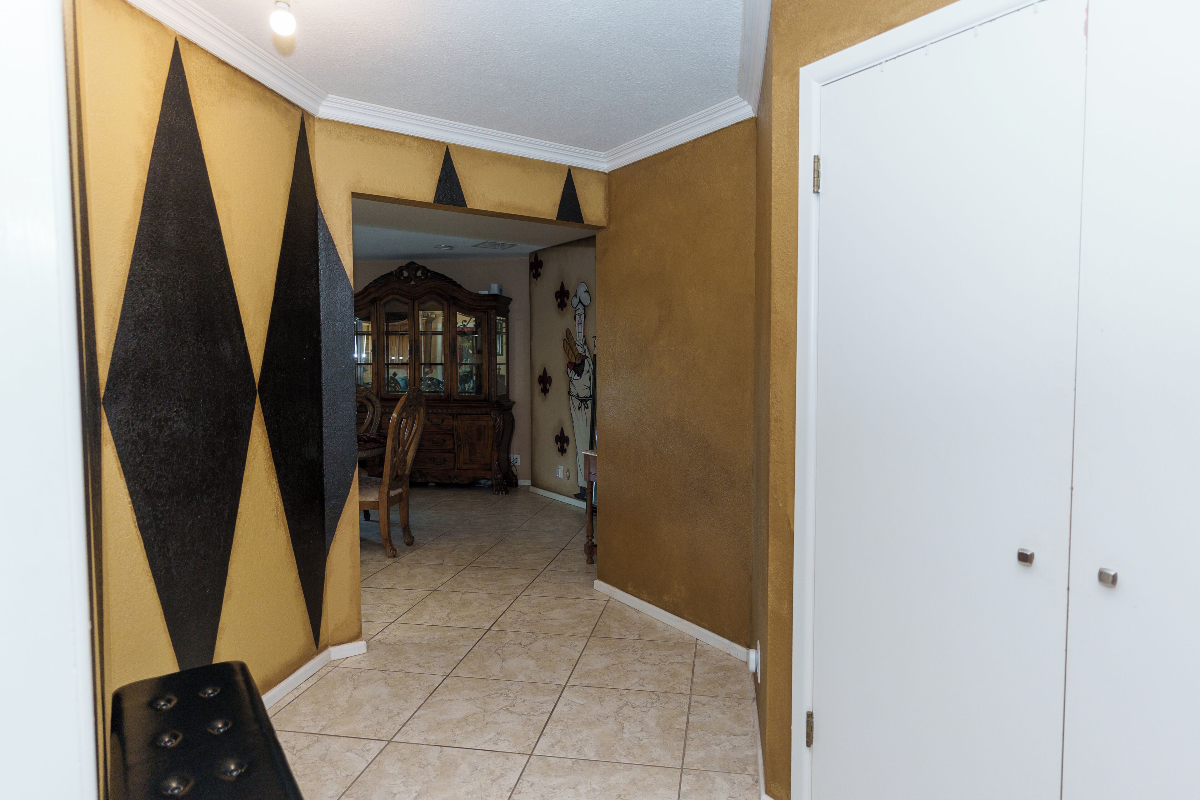 A hallway with a tiled floor, a wooden cabinet, and a door.