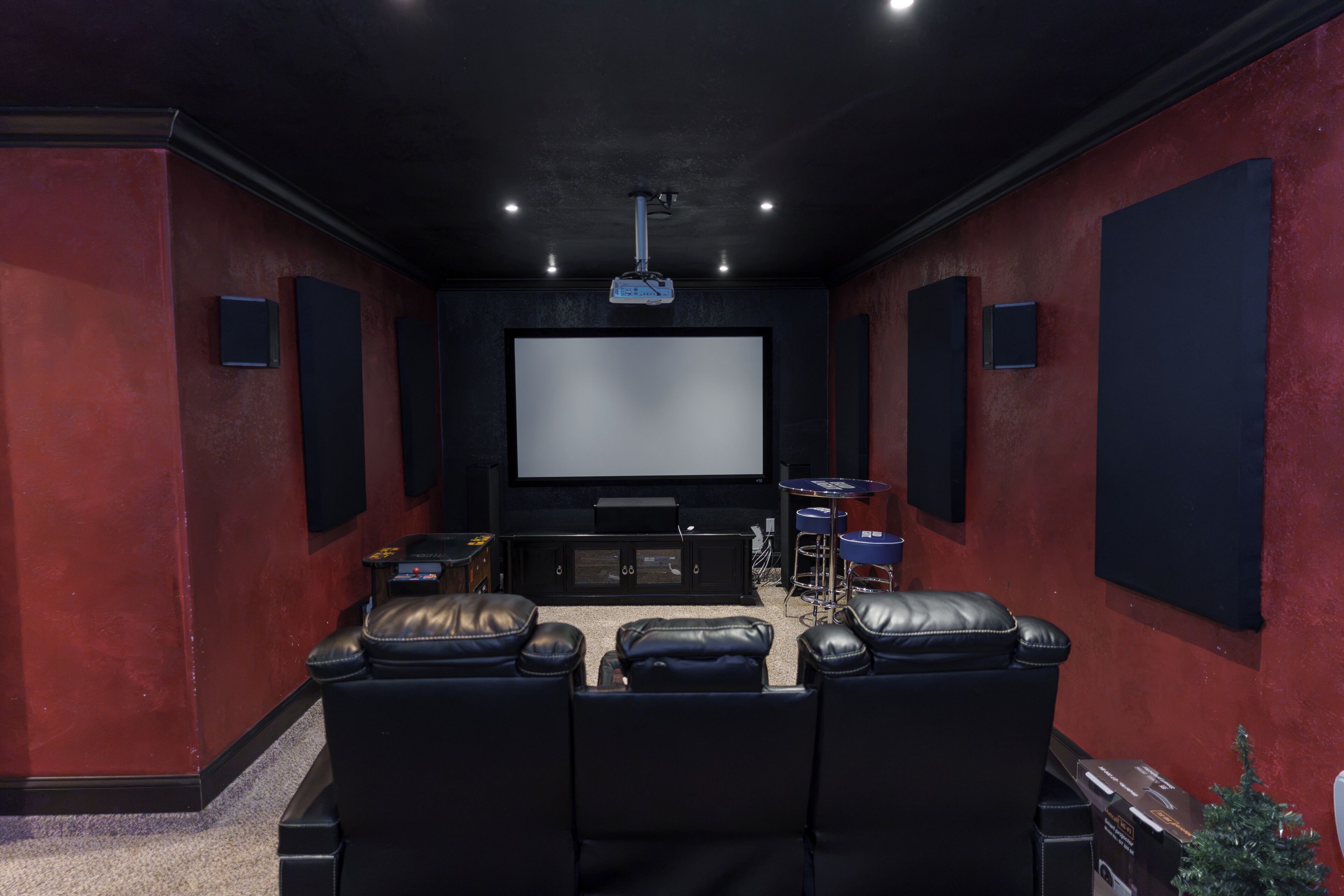 A home theater room with a large flat-screen TV, black leather seating, and a popcorn machine.