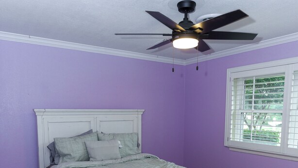 Quarto com cama, ventilador de teto e janela.