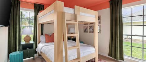 A bunk bed room with a window, a nightstand with a lamp, and a green curtain.