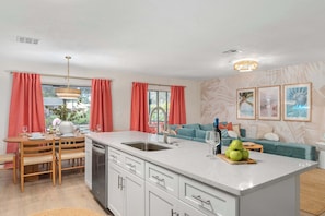 A modern kitchen with a central island, a dining area with a table and chairs, and a living area with a sofa and a coffee table.