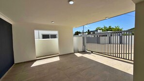 A spacious indoor area with a tiled floor, a metal gate, and a window with a metal grille. - Family Home in a Private Residential Complex (Licey al Medio)