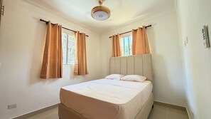 Ein Schlafzimmer mit Bett, Vorhängen, Deckenventilator und Fenster.