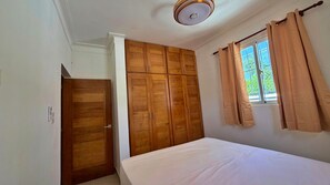 A bedroom with a bed, wooden wardrobe, and a window with curtains. - Family Home in a Private Residential Complex (Licey al Medio)