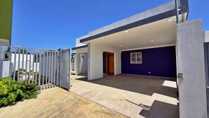 A modern building with a covered entrance, a gated driveway, and a clear sky. - Family Home in a Private Residential Complex (Licey al Medio)