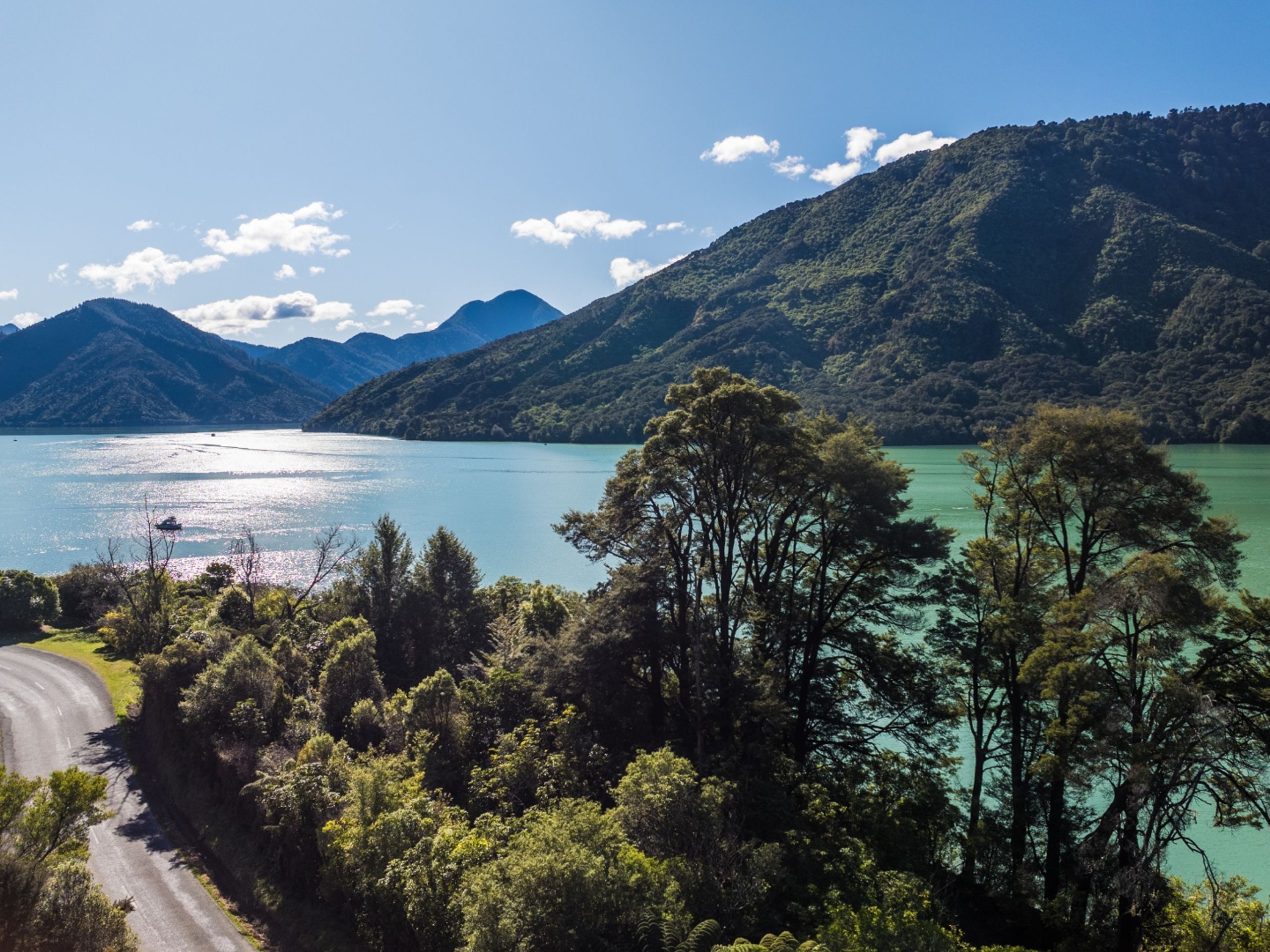 A coastal road with a view of a lake and mountains.