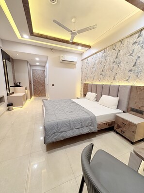 A modern bedroom with a bed, bedside tables, a chair, a ceiling fan, and an air conditioning unit. - Fabulous 1-bedroom apartment with AC in lively Lucknow (LUCKNOW)