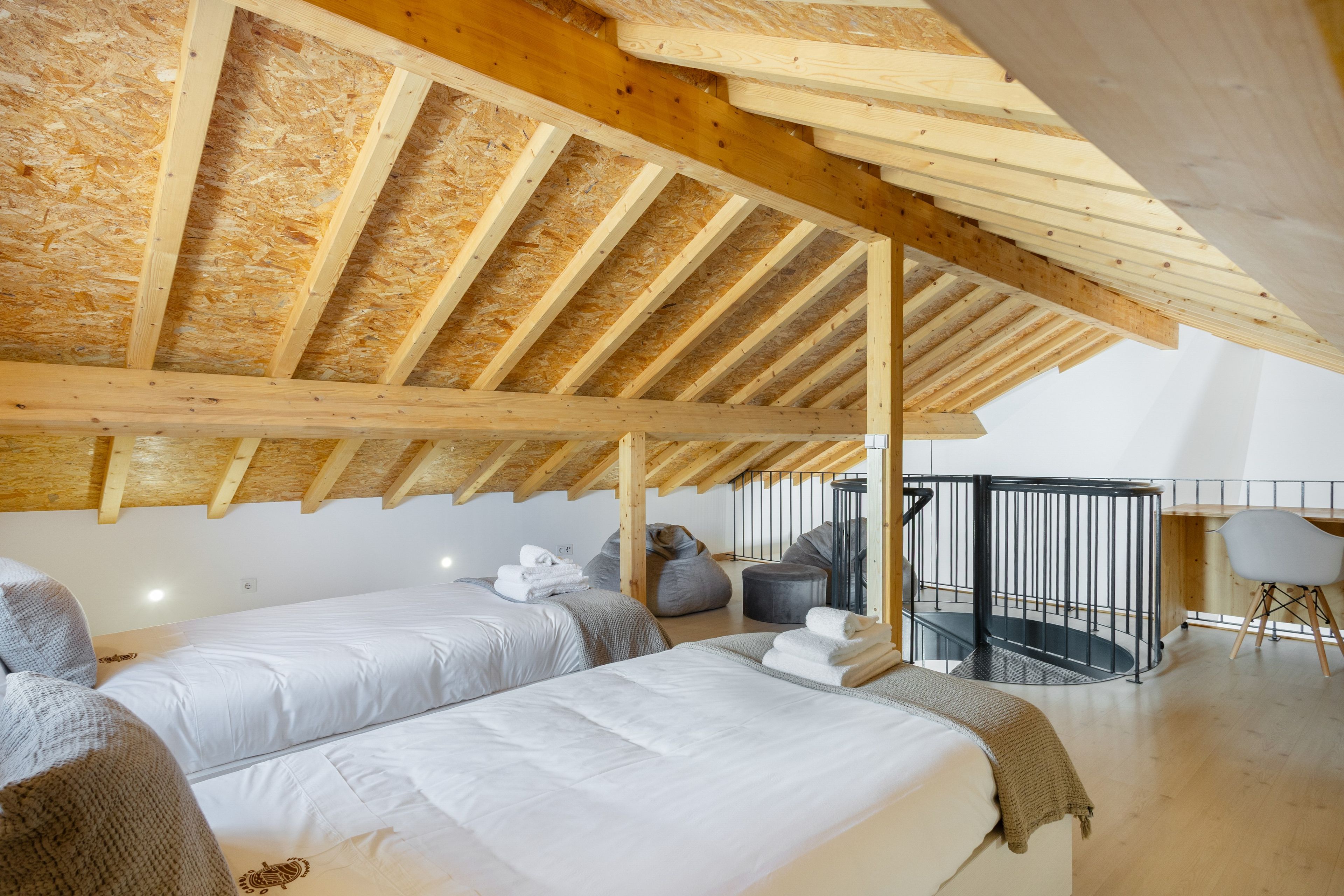 A bedroom with two beds, a balcony, and a view of the sky.
