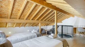 A bedroom with two beds, a balcony, and a view of the sky.