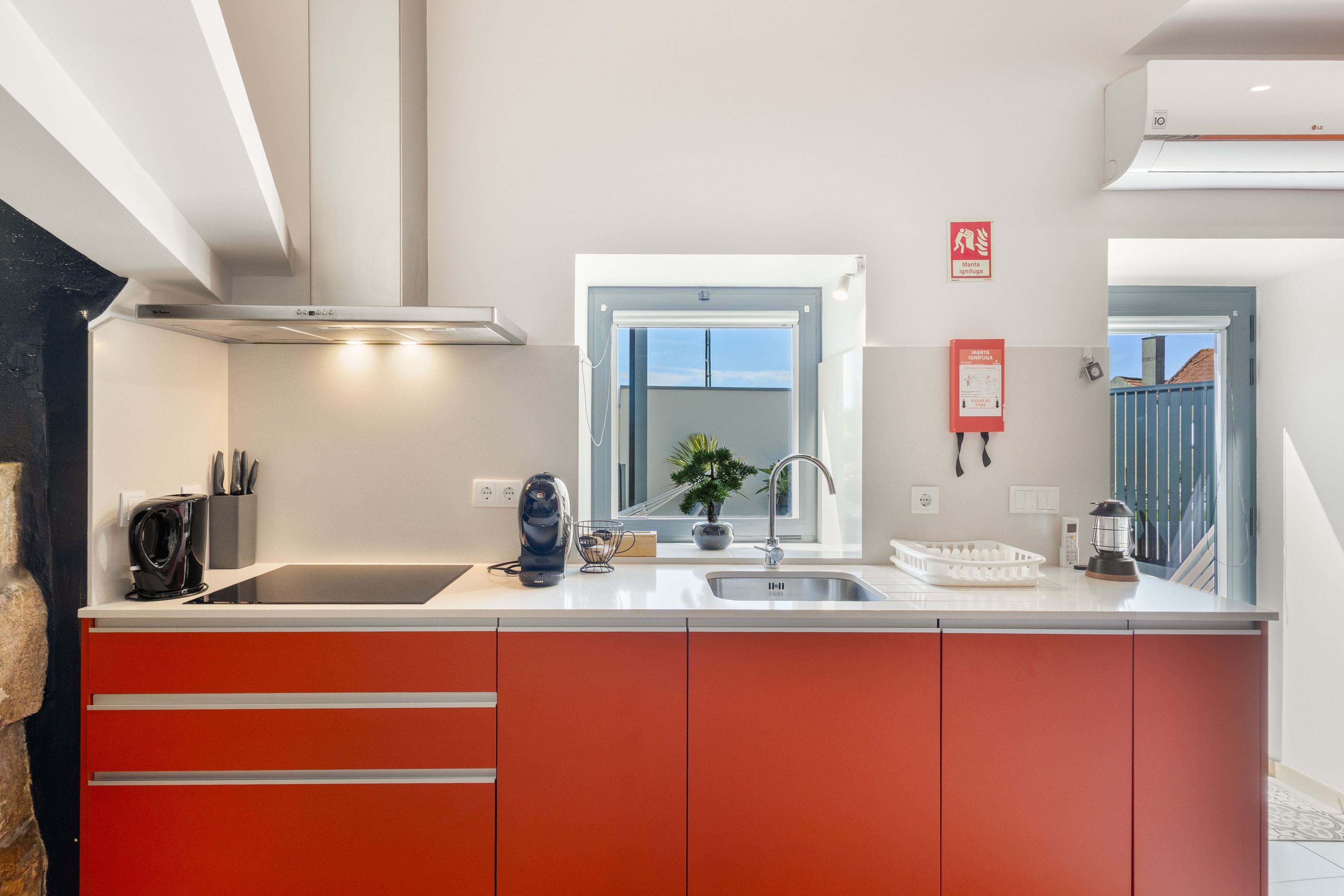 A modern kitchen with a stainless steel sink, a coffee machine, and a red cabinet.