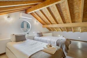 A bedroom with two beds, a mirror, and a skylight.