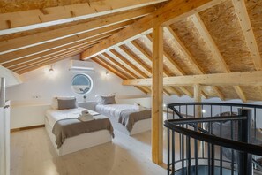 Un dormitorio con dos camas, un tragaluz y una estructura de techo de madera.