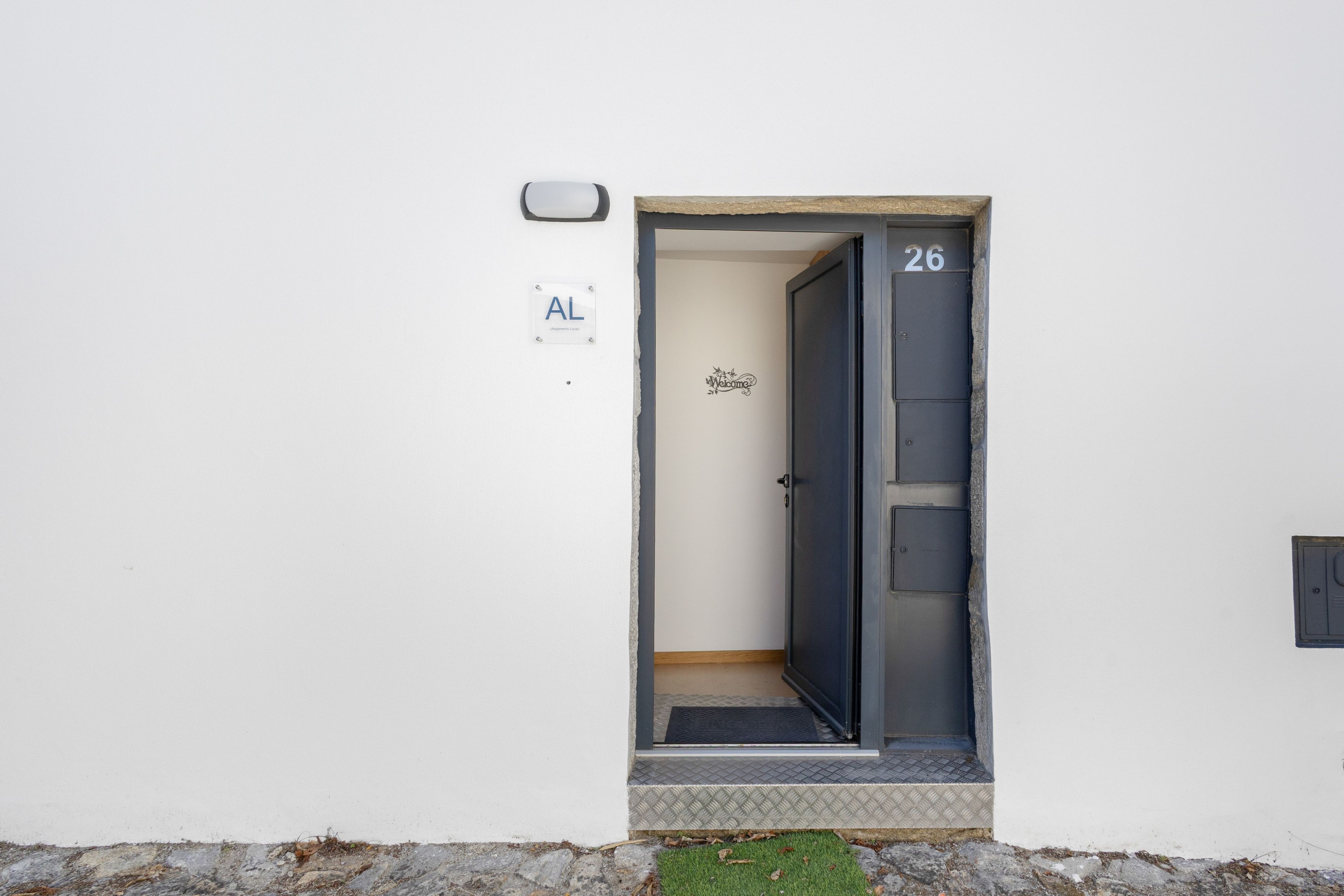 Een deur met het nummer 26, een bord met de tekst 'Welkom' en een bord waarop 'Apartments Local' staat.
