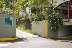 Schild von Club Fuce mit Auflistung der Annehmlichkeiten, Eingang einer Parkgarage und umliegendes Grün.
